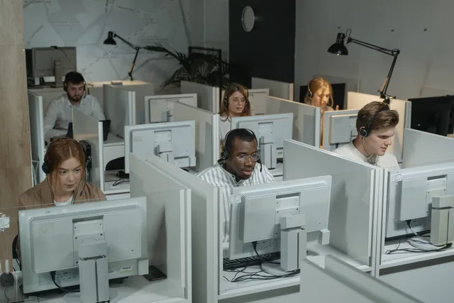 Professional customer support team working with headsets in a modern office environment. Beschäftigung in der Schweiz messen: Daten, Begriffe und Quellen